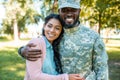 smiling african american soldier in military uniform hugging girlfriend