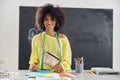 Smiling African-American student with palettes and colored paper sheets at table at sewing class Royalty Free Stock Photo