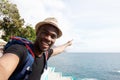 Smiling african american travel man taking selfie by the sea and pointing finger Royalty Free Stock Photo