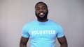 Smiling African-American volunteer in blue t-shirt looking at camera, help