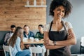 Smiling african american waitress standing with customers sitting behind