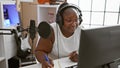 Smiling african american woman, a confident musician, composing a soulful song in a music studio, engrossed in her musical world Royalty Free Stock Photo