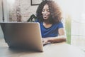 Smiling african american woman using laptop while sitting at wooden table in the living room.Horizontal,blurred Royalty Free Stock Photo