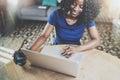 Smiling african american woman using laptop while sitting at wooden table in the living room.Horizontal.Blurred Royalty Free Stock Photo