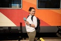 Smiling African American woman using mobile phone while waiting for train at railway station. Royalty Free Stock Photo