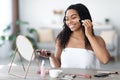 Smiling african american woman wrapped in towel putting make up Royalty Free Stock Photo