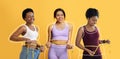 Smiling african american young females, overweight ladies drawn around, checking waist with measuring tape Royalty Free Stock Photo