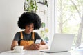 Smiling African hipster teenage girl using smart phone sitting at cafe table. Royalty Free Stock Photo