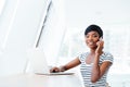 Smiling african american young woman accountant using laptop and smartphone