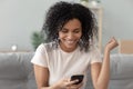 Smiling black woman feel excited read good news on cellphone Royalty Free Stock Photo