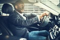 Smiling African businessman driving his car through city streets Royalty Free Stock Photo