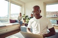 Smiling African businessman sitting at his desk using a laptop Royalty Free Stock Photo