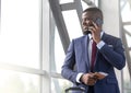 Smiling african businessman talking on phone at the airport waiting lounge Royalty Free Stock Photo