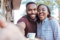 Smiling African couple taking selfies together at a sidewalk cafe Royalty Free Stock Photo