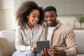 Smiling African couple with wireless earphones using digital tablet indoors Royalty Free Stock Photo