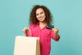 Smiling african girl in casual clothes hold package bag with purchases after shopping, credit card isolated on blue Royalty Free Stock Photo