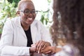 Smiling african girl doctor shaking hands with latin american female patient. Confidence of the doctor and patient. Voluntary Royalty Free Stock Photo