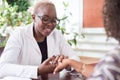 Smiling african girl doctor shaking hands with latin american female patient. Confidence of the doctor and patient. Voluntary Royalty Free Stock Photo