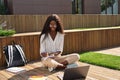 Smiling African girl student studying online using laptop sitting outside. Royalty Free Stock Photo