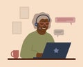 A smiling African grandmother in headphones with a laptop. An elderly woman communicates, studies, works or shoppes