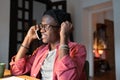 Smiling African guy college student talking on phone while studying at home, taking break from study Royalty Free Stock Photo