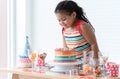 Smiling African little kid girl in cute dress, surprised on birthday party, looking at beautiful rainbow cake decorated with sugar Royalty Free Stock Photo