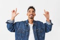 Smiling african man in denim jacket pointing with forefingers Royalty Free Stock Photo