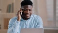 Smiling african man male businessman employee freelancer multitasking worker sit at home office talk on cellphone look