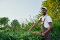 Smiling african man in overall cutting outgrown bushes
