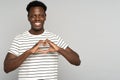 Smiling African man showing heart sign with fingers, feels grateful for love, thankful and support.