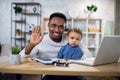 Smiling african man sitting at home office with his cute son Royalty Free Stock Photo