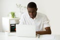Smiling african man using laptop sitting at home office desk Royalty Free Stock Photo