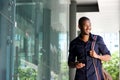 Smiling african man walking with mobile phone and bag Royalty Free Stock Photo