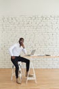 Smiling African man working at home sitting at the table. Concept of young people using laptop Royalty Free Stock Photo