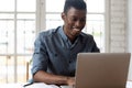 African office employee sitting at workplace typing on laptop