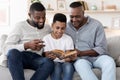 Smiling African Preteen Boy Reading Book With Dad And Grandpa At Home Royalty Free Stock Photo