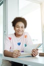 Smiling African student or pupil girl is reading a book in library at school. She is enjoy for learning at home for homeschool. Royalty Free Stock Photo