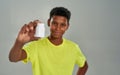 Smiling african teenage boy bringing up a white container with medication during its promotion at a camera while