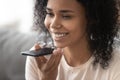 Smiling african woman activate virtual digital voice assistant on smartphone Royalty Free Stock Photo