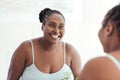 Smiling African woman looking at her reflection in a mirror