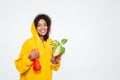 Smiling african woman in raincoat holding plant Royalty Free Stock Photo