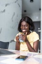 Smiling young african woman using laptop computer while sitting at home with cup of coffee Royalty Free Stock Photo