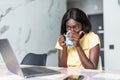 Smiling young african woman using laptop computer while sitting at home with cup of coffee Royalty Free Stock Photo