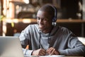 Smiling african young man student wearing headphones study online