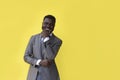 Smiling Afro-American businessman with folded arms against yellow background Royalty Free Stock Photo