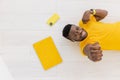 Smiling Afro American student or freelancer standing near the wall in trendy yellow t-shirt, having online call with Royalty Free Stock Photo