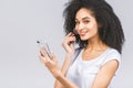 Smiling afro american woman applying makeup powder with brush isolated on a grey background. Using phone Royalty Free Stock Photo