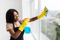 Smiling afro american woman cleaning glass window at home Royalty Free Stock Photo