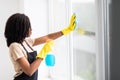 Smiling afro american woman cleaning glass window at home Royalty Free Stock Photo