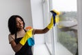 Smiling afro american woman cleaning glass window at home Royalty Free Stock Photo